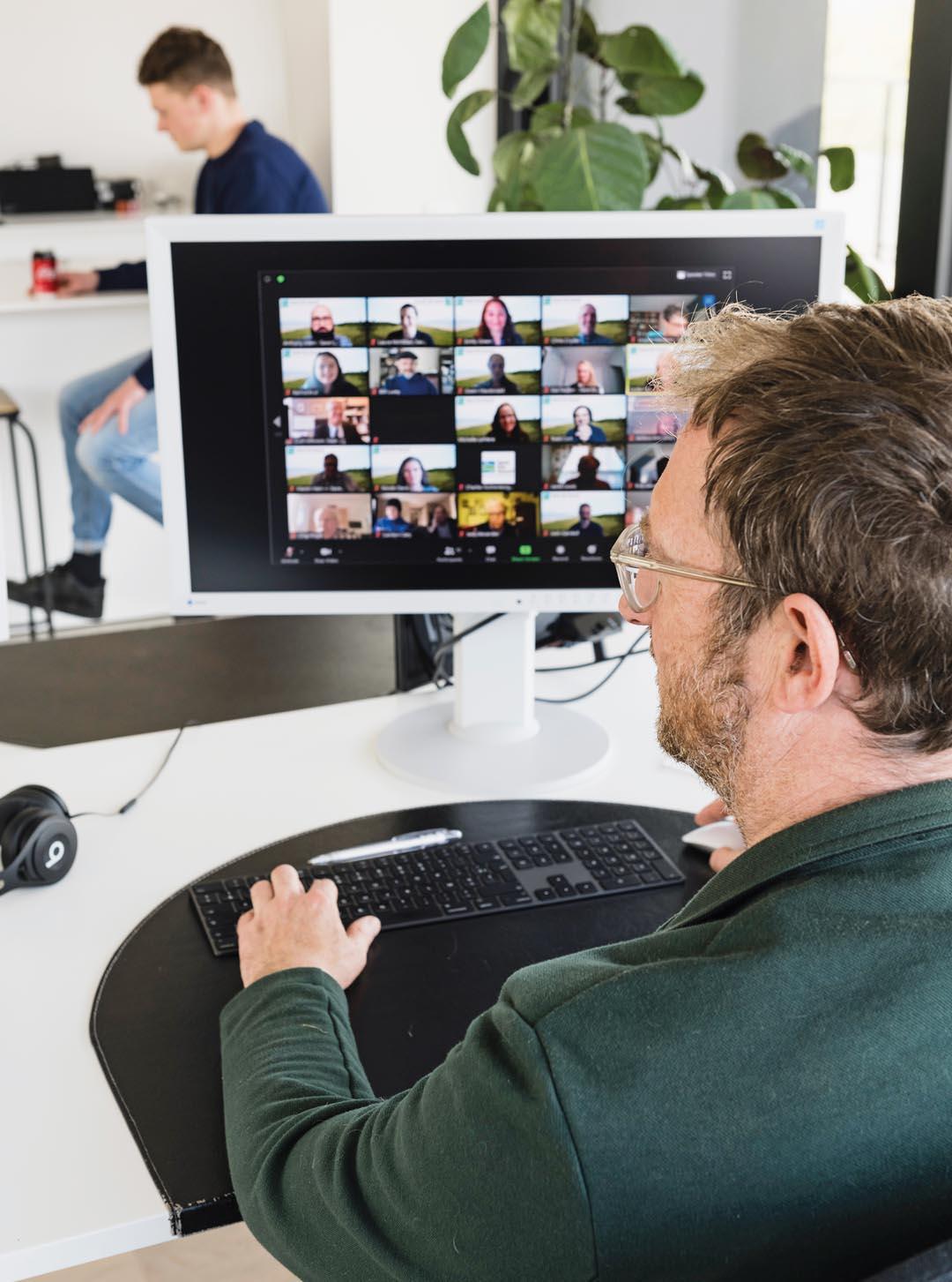 Een man achter zijn computer in een grote online meeting