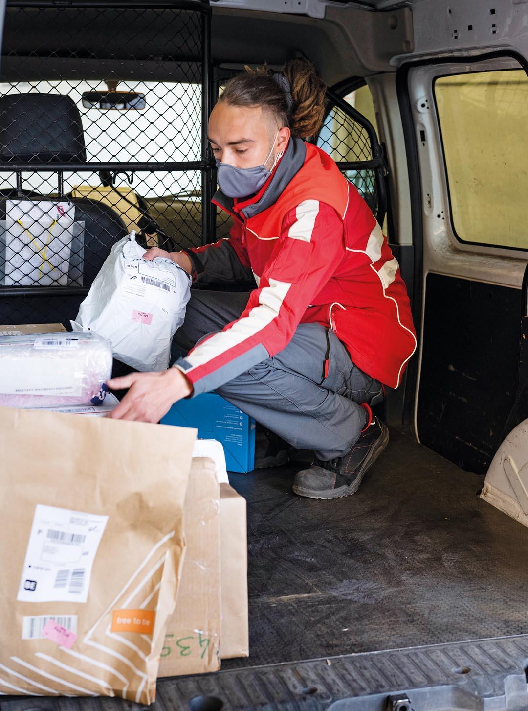 Een postbode neemt pakjes uit bestelwagen