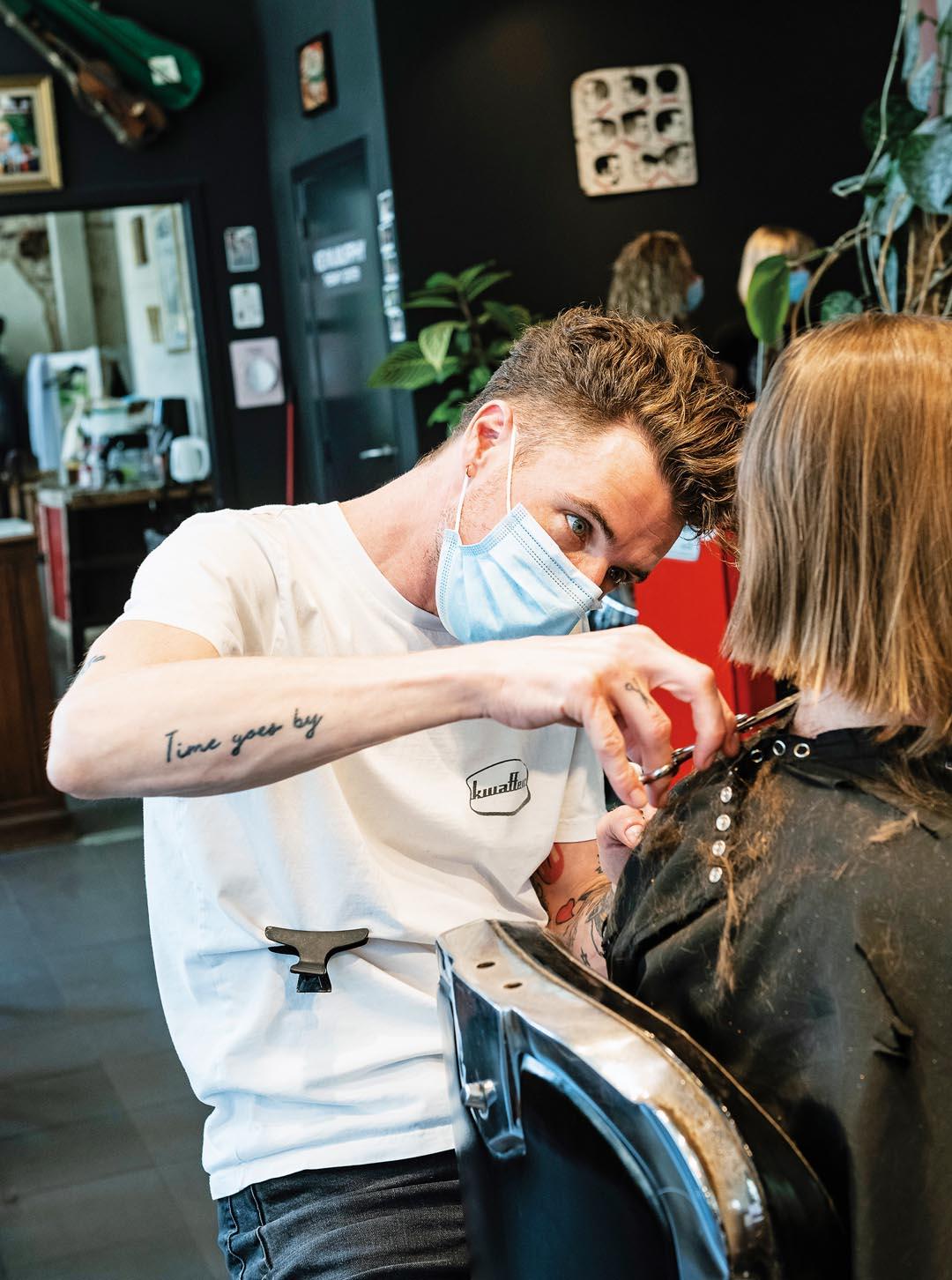 Un coiffeur coupe les cheveux d'un client