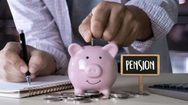 Pensioenen: een man steekt enkele muntstukken in een spaarvarken voor zijn toekomstig pensioen  terwijl hij zijn uitgaven berekent