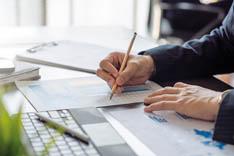 Iemand schrijft met potlood op grafieken op papier A hand writing on charts on a paper