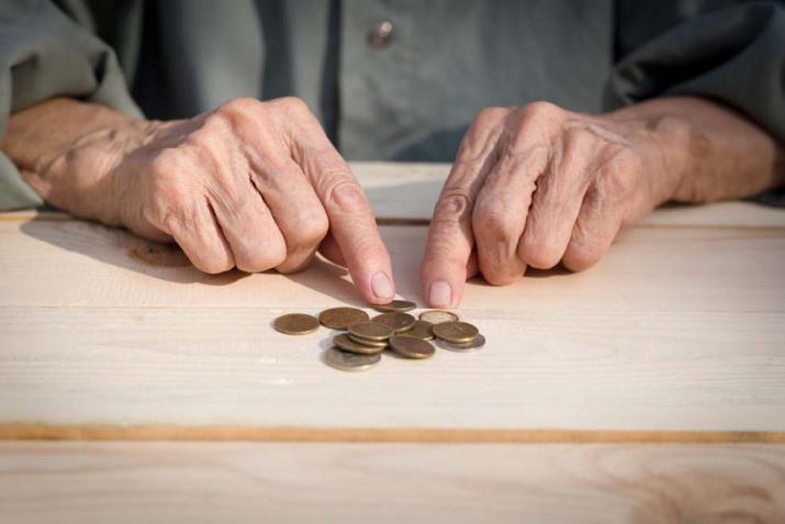 Pensioenen: een oudere man zittend aan zijn bureau en munten aan het tellen Pensioenen: een oudere man zittend aan zijn bureau en munten aan het tellen