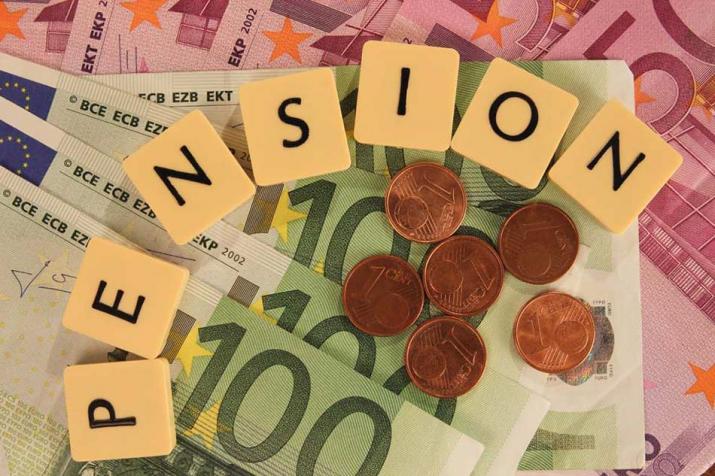 Pensioenen: verschillende eurobiljetten en muntstukken met Scrabble-letters die 'pension' spellen