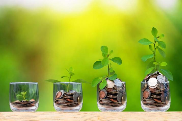 Pensioenen: verschillende glazen potjes met muntstukken op een rij waaruit plantjes groeien alsook het aantal muntstukken