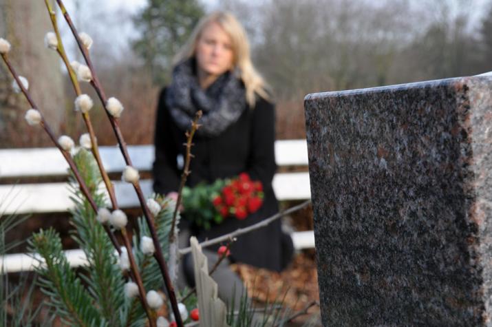 Pensioenen: een vrouw op begraafplaats zit bij een graf van een diebare in diepe droefheid Pensioenen: een vrouw op begraafplaats zit bij een graf van een diebare in diepe droefheid