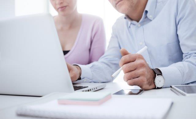 Two colleagues work together on a computer